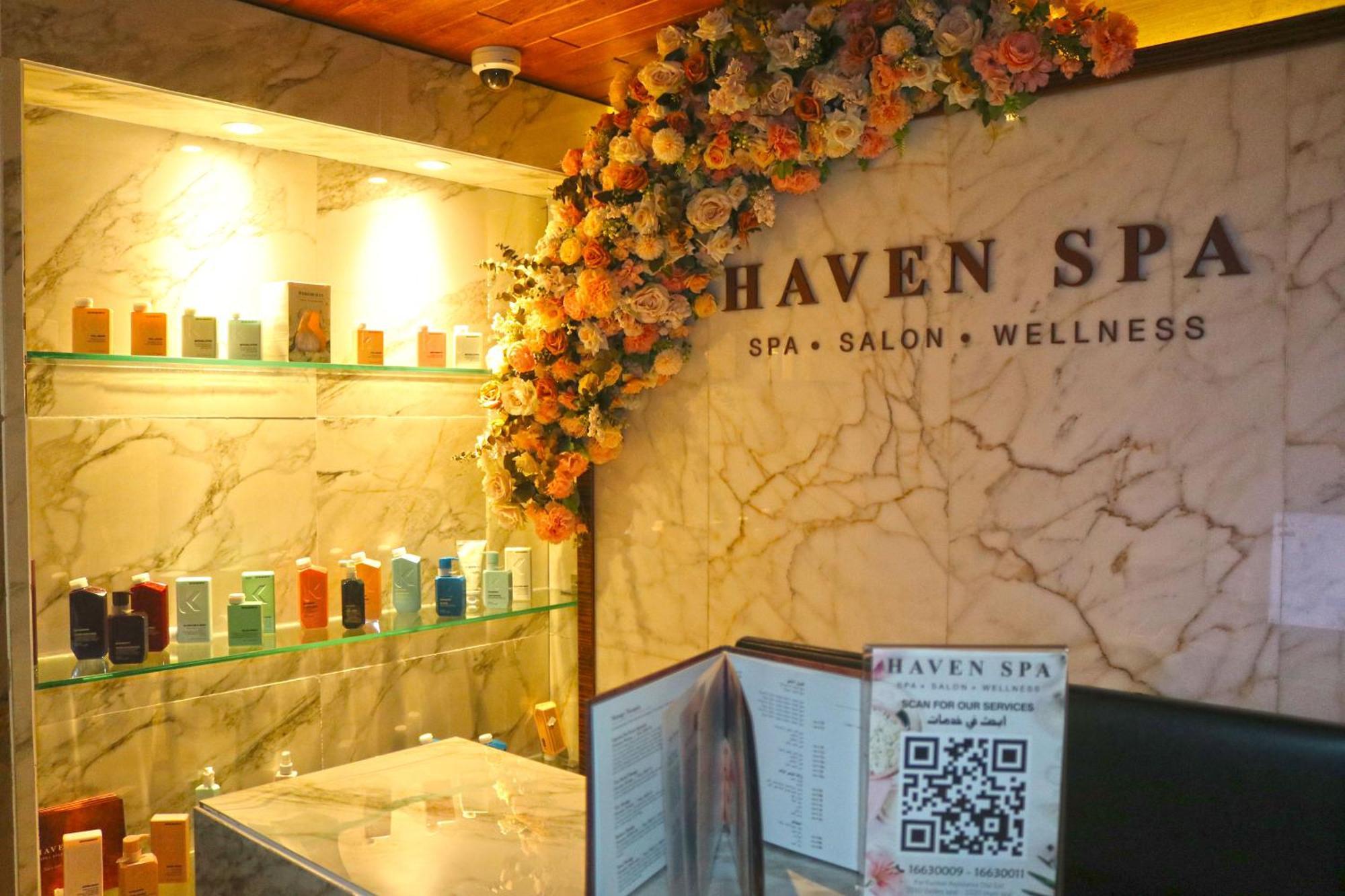 라구나 비치 럭셔리 리조트 앤 스파 마나마 외부 사진 The photo shows the interior of a spa called "Haven Spa." The wall is decorated with beautiful artificial flowers, creating an inviting atmosphere. There are several shelves displaying various colorful bottles and products, likely for skincare or wel