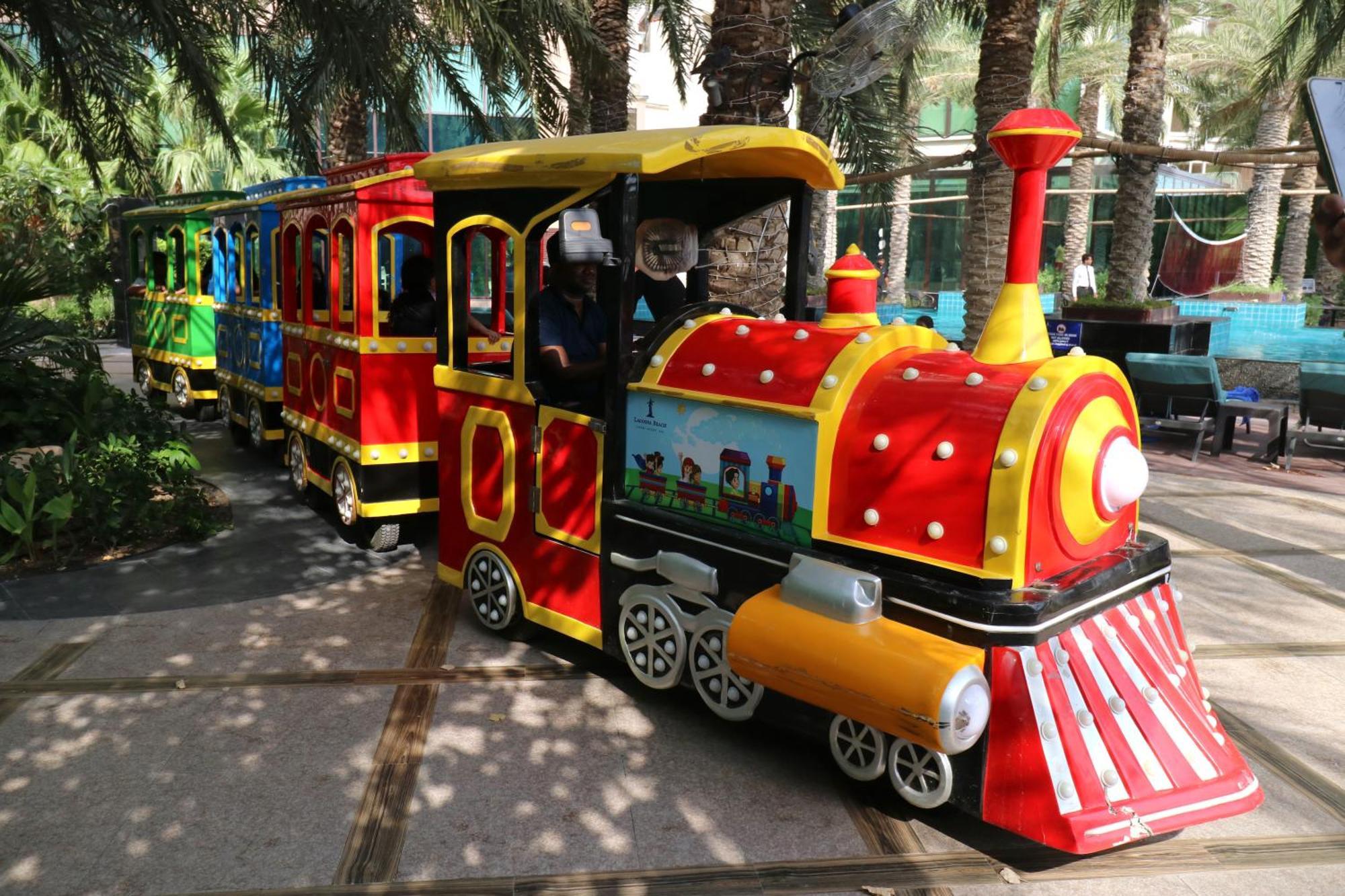 라구나 비치 럭셔리 리조트 앤 스파 마나마 외부 사진 The photo shows a colorful miniature train. It features a vibrant design with bright red, yellow, and blue colors. The front of the train resembles a classic steam engine, complete with a prominent smokestack. The train is designed to resemble a fun 