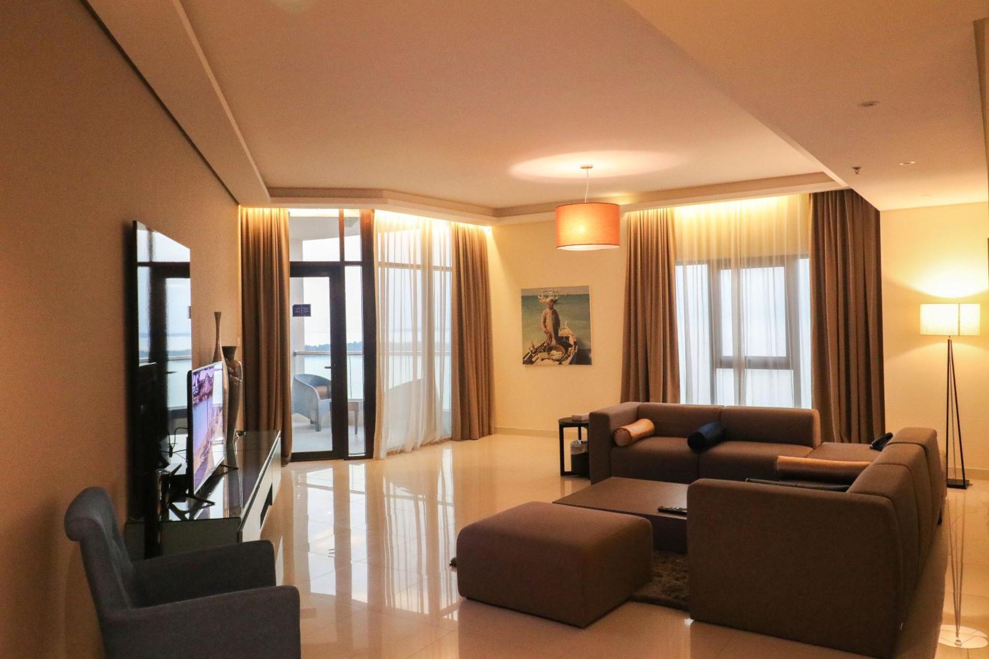 라구나 비치 럭셔리 리조트 앤 스파 마나마 외부 사진 The photo shows a modern living room with a spacious and elegant design. It features a large couch in neutral tones, a soft ottoman, and a stylish coffee table. The walls are painted in a light color, and there are large windows with sheer curtains a