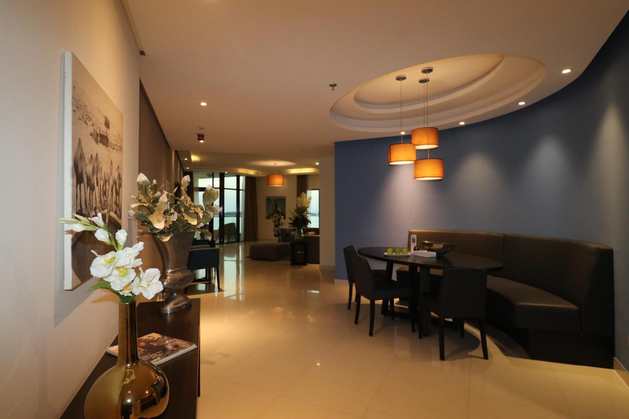 라구나 비치 럭셔리 리조트 앤 스파 마나마 외부 사진 The photo showcases an interior space, likely a modern lounge or reception area. It features a combination of soft lighting, neutral-colored walls, and decorative elements. There are elegant light fixtures hanging from the ceiling, and a curved blue 